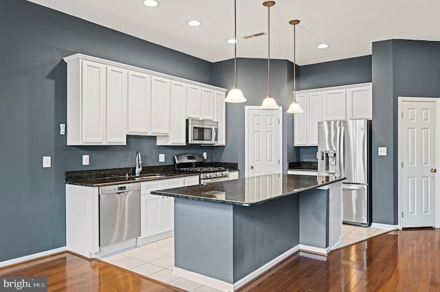 kitchen featuring appliances with stainless steel finishes, a sink, light wood-style flooring, and white cabinets