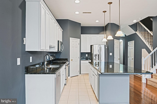 kitchen with a kitchen island, appliances with stainless steel finishes, white cabinets, and a sink