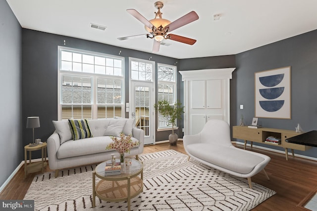 interior space featuring a ceiling fan, baseboards, visible vents, and wood finished floors