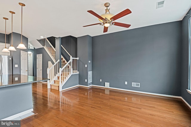 spare room featuring visible vents, stairway, baseboards, and wood finished floors