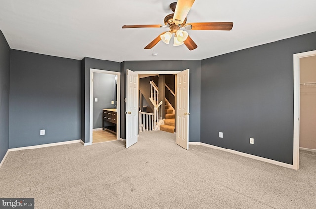 unfurnished bedroom featuring carpet floors, a walk in closet, a closet, and baseboards