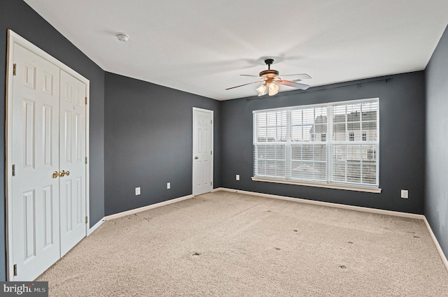 carpeted empty room with ceiling fan and baseboards