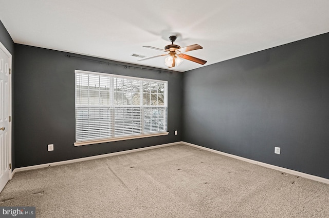 unfurnished room with carpet floors, visible vents, baseboards, and a ceiling fan