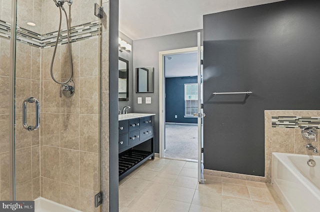 full bathroom with a garden tub, a shower stall, vanity, tile patterned flooring, and baseboards