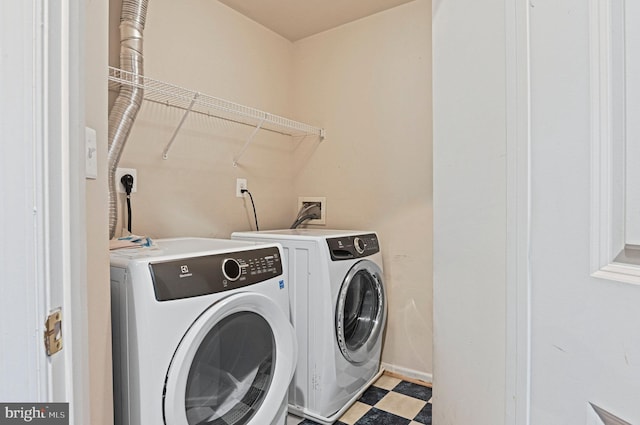 clothes washing area with washer and dryer, laundry area, and light floors