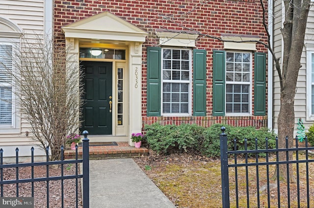 entrance to property featuring brick siding and fence