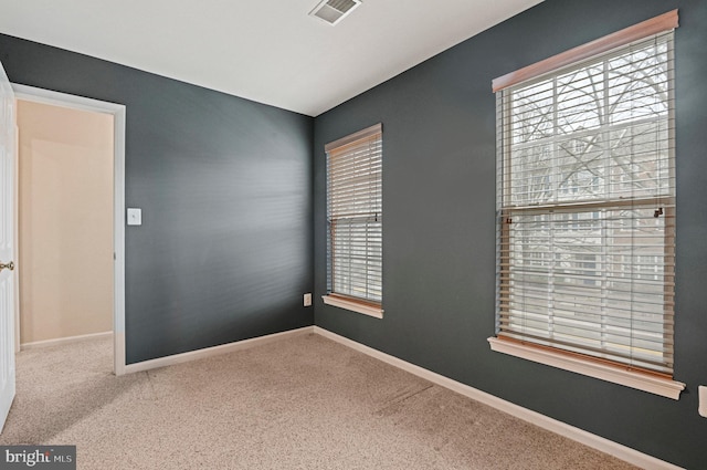 carpeted spare room with visible vents and baseboards