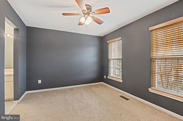 carpeted spare room with visible vents, ceiling fan, and baseboards