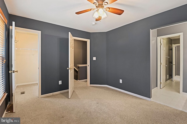 unfurnished bedroom with baseboards, ceiling fan, carpet, a spacious closet, and a closet