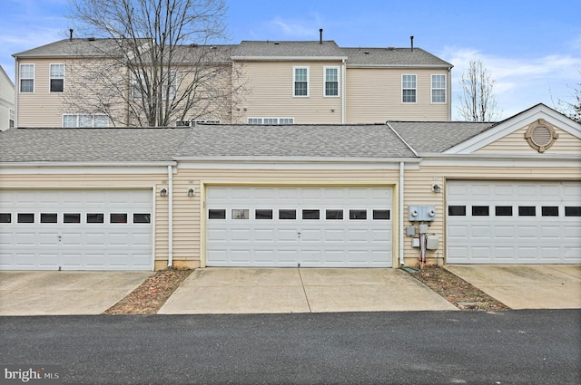 townhome / multi-family property featuring a garage, driveway, and roof with shingles