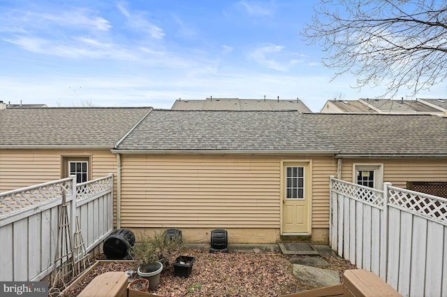 back of house with roof with shingles and a fenced backyard