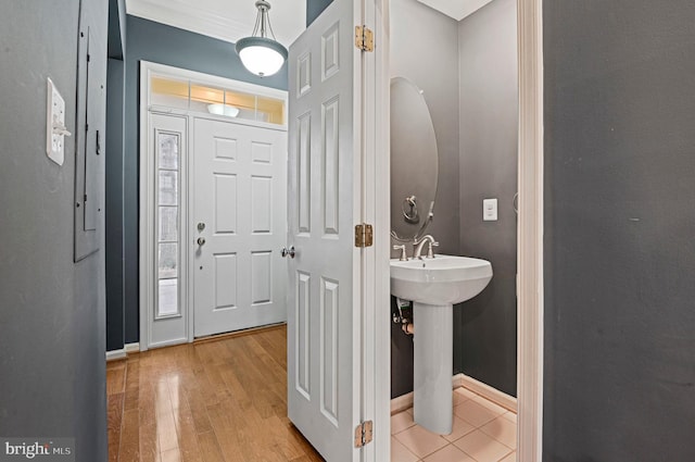 bathroom featuring a sink, ornamental molding, wood finished floors, and baseboards