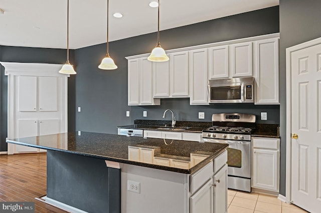 kitchen with white cabinets, a kitchen island, stainless steel appliances, and a sink