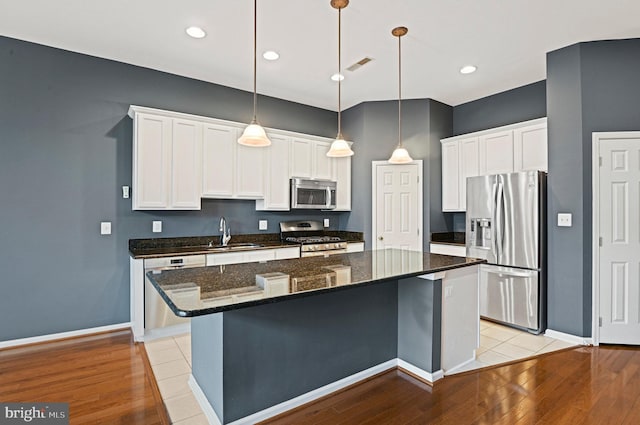 kitchen featuring visible vents, white cabinets, a center island, stainless steel appliances, and a sink