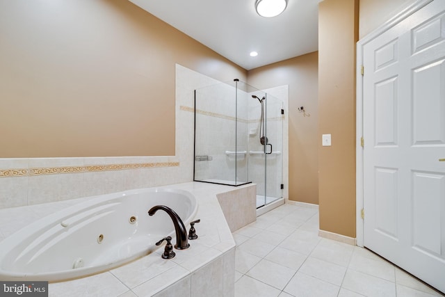 bathroom with a stall shower, a jetted tub, baseboards, and tile patterned floors