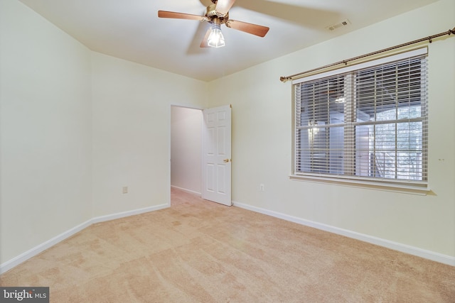 carpeted empty room featuring a ceiling fan, visible vents, and baseboards