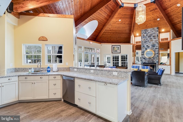 kitchen featuring a fireplace, a sink, open floor plan, dishwasher, and light wood finished floors