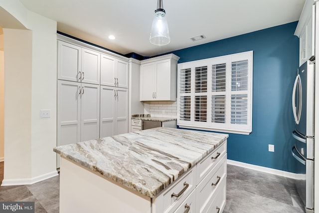 kitchen featuring baseboards, visible vents, white cabinets, freestanding refrigerator, and light stone countertops