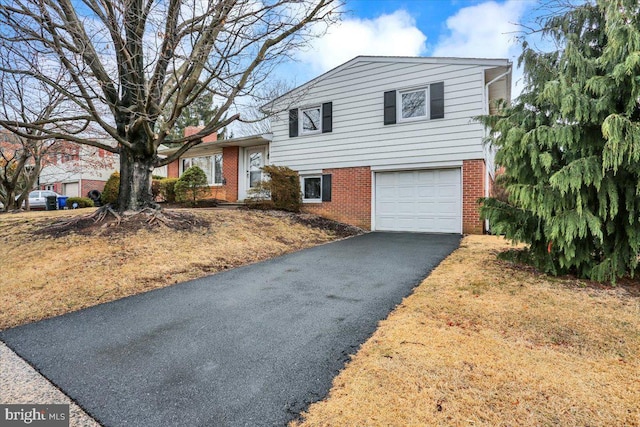 tri-level home with a garage, aphalt driveway, and brick siding