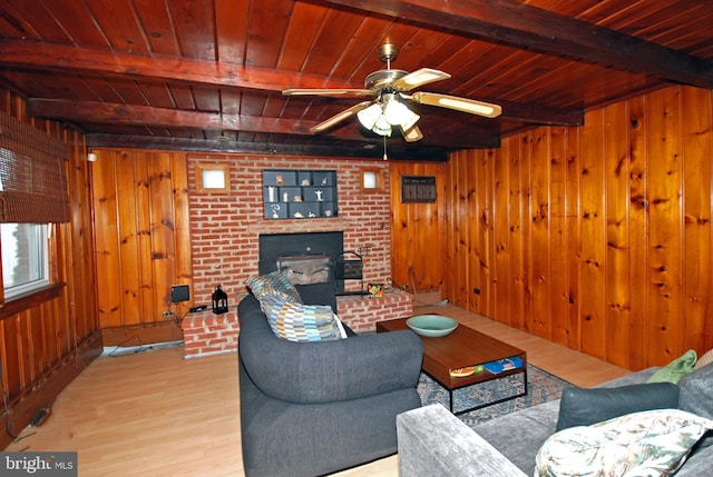 living area featuring beam ceiling, ceiling fan, wood walls, wood finished floors, and wooden ceiling