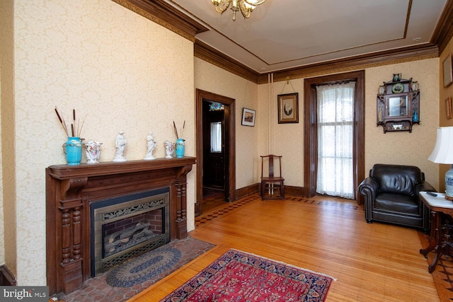 living room with ornamental molding, a fireplace, light wood-style flooring, and wallpapered walls