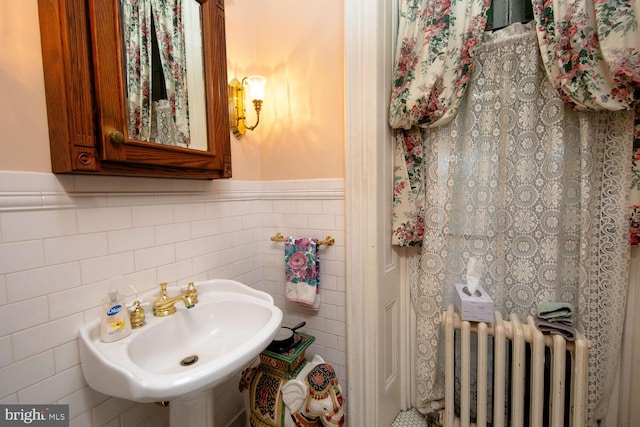 bathroom with wainscoting, a sink, tile walls, and radiator heating unit