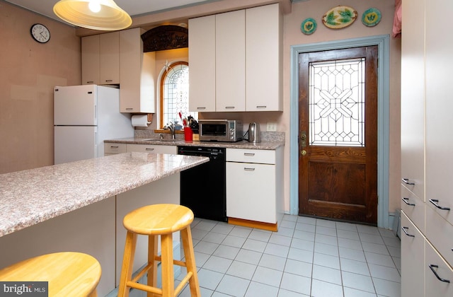 kitchen with a sink, white cabinets, black dishwasher, a kitchen breakfast bar, and freestanding refrigerator