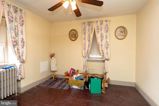 recreation room featuring radiator, wood-type flooring, baseboards, and a ceiling fan