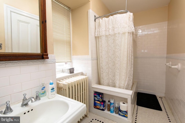 bathroom featuring tile patterned flooring, radiator, a sink, and tile walls