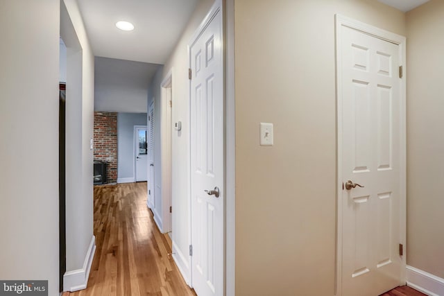 hallway featuring light wood-style flooring and baseboards