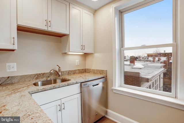 kitchen featuring white cabinetry, dishwasher, a sink, and light stone countertops