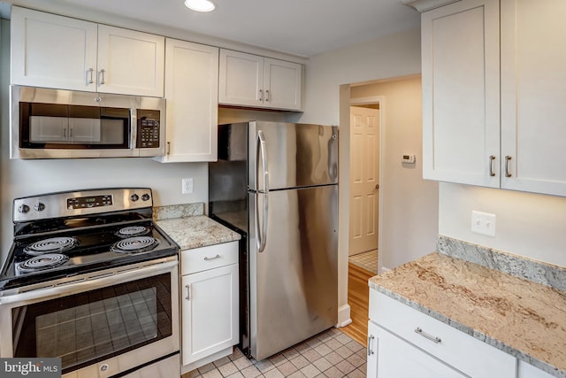 kitchen with light stone countertops, white cabinetry, and appliances with stainless steel finishes