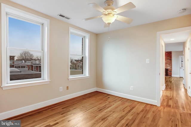 empty room featuring light wood-style flooring, visible vents, baseboards, and ceiling fan