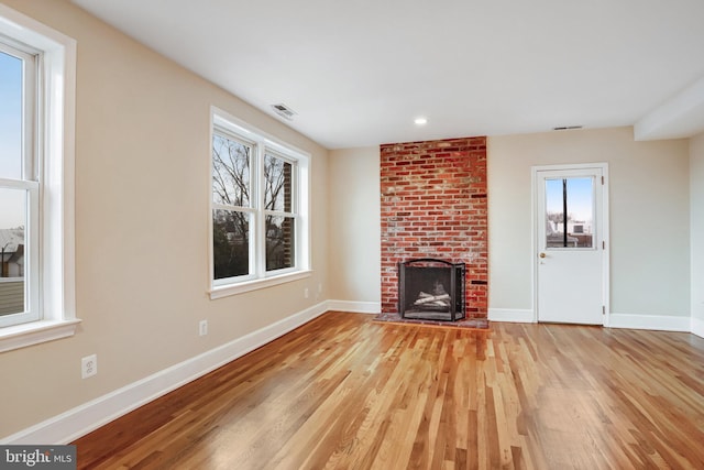 unfurnished living room with light wood finished floors, a fireplace, and baseboards