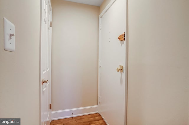 corridor featuring baseboards and light wood finished floors