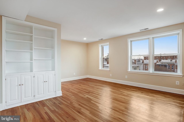 spare room with light wood finished floors, baseboards, visible vents, and recessed lighting