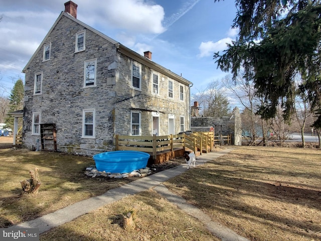 exterior space with a deck, stone siding, and a chimney