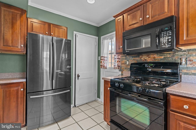 kitchen featuring light tile patterned flooring, light countertops, decorative backsplash, black appliances, and crown molding