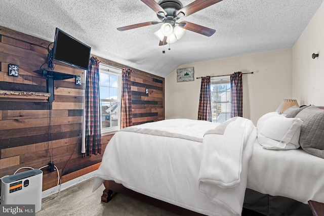 bedroom featuring wooden walls, a ceiling fan, lofted ceiling, a textured ceiling, and carpet flooring