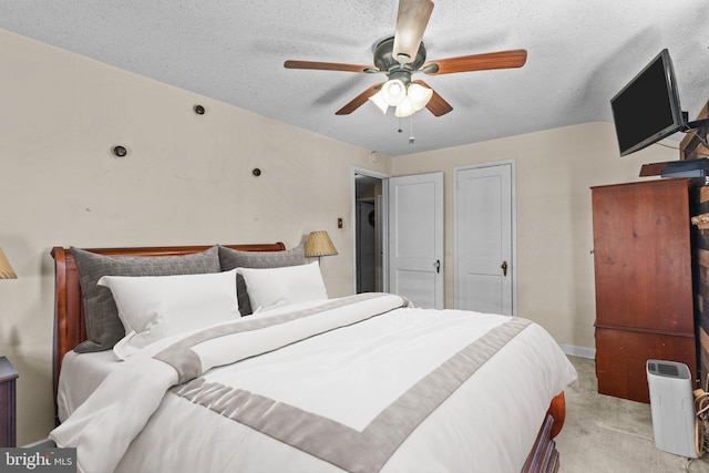 bedroom with ceiling fan, baseboards, a textured ceiling, and light colored carpet