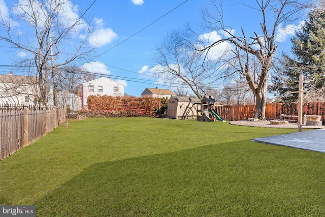 view of yard featuring a fenced backyard, a shed, a playground, and an outdoor structure