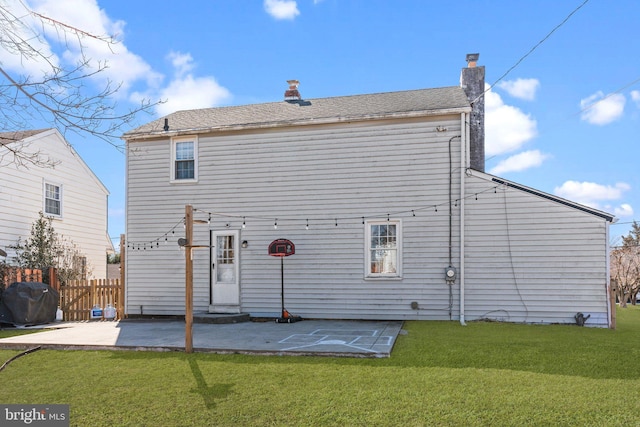 back of house featuring a patio, a yard, a chimney, and fence