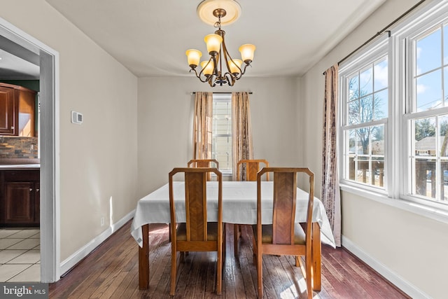 dining area with a notable chandelier, baseboards, and hardwood / wood-style flooring