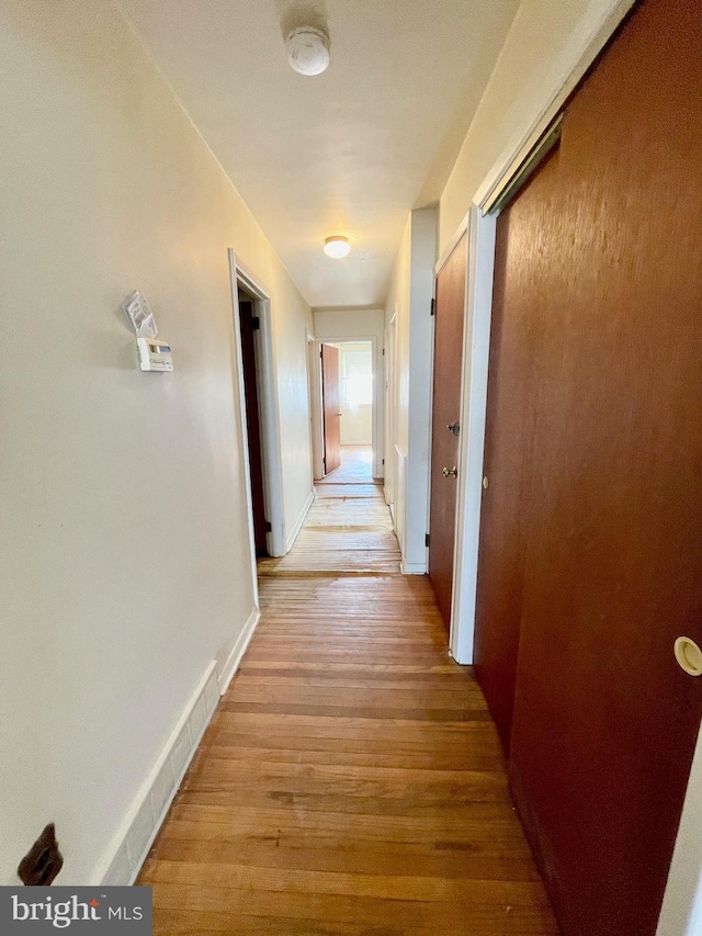 hall featuring baseboards and light wood finished floors