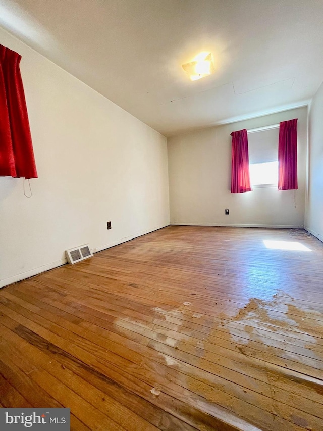 empty room featuring wood-type flooring and visible vents