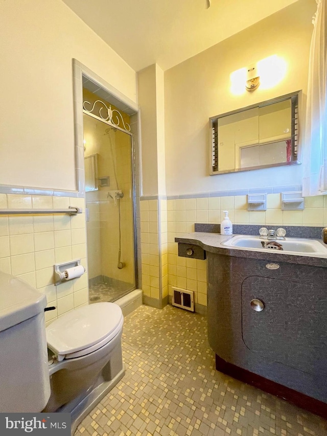 full bathroom featuring toilet, a wainscoted wall, vanity, tile walls, and a stall shower