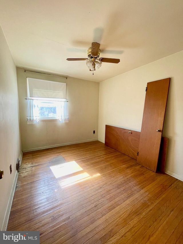 spare room featuring ceiling fan, wood-type flooring, and baseboards