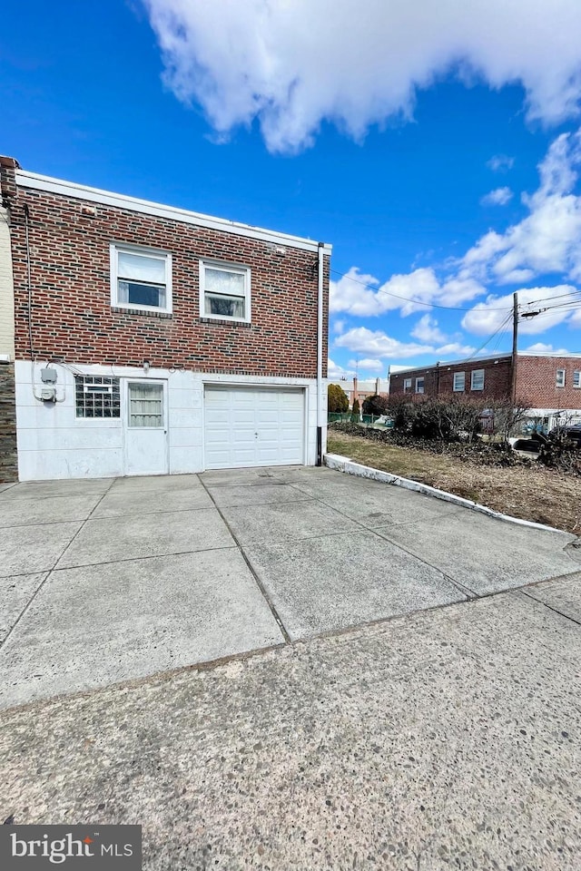 view of property exterior with a garage, concrete driveway, and brick siding