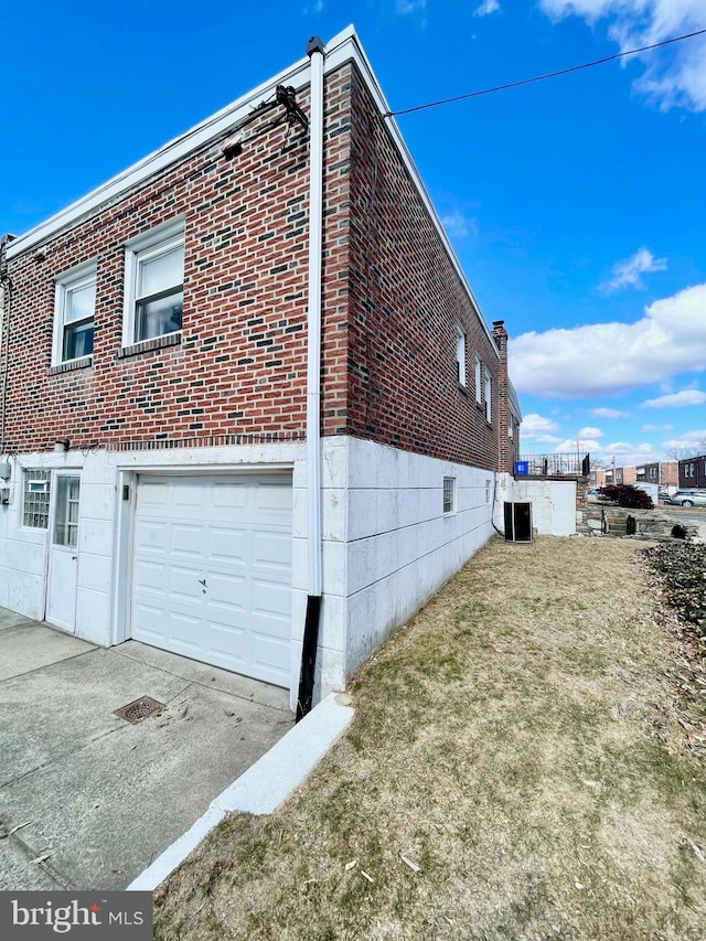 view of property exterior featuring a garage, brick siding, a yard, and central air condition unit