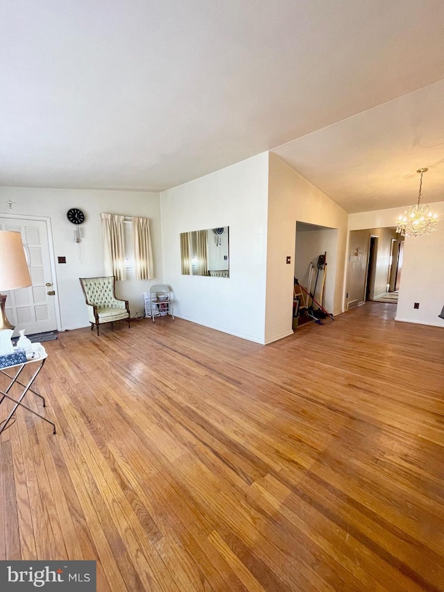 unfurnished living room with a notable chandelier and wood finished floors